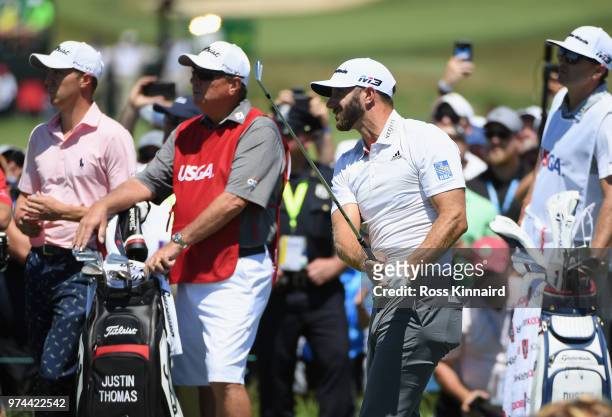 Dustin Johnson of the United States plays his shot from the first tee as Justin Thomas of the United States looks on during the first round of the...