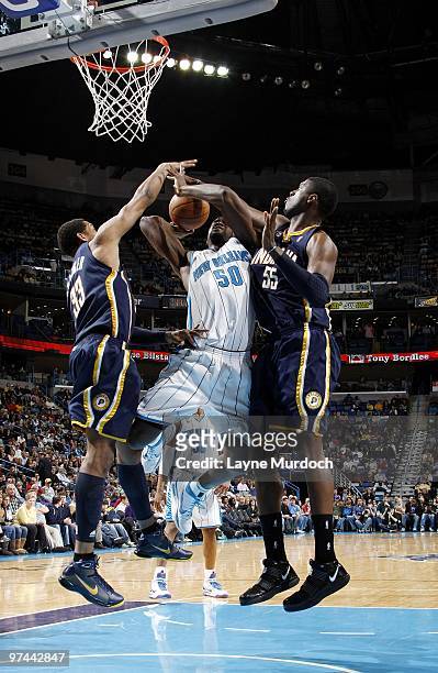 Emeka Okafor of the New Orleans Hornets goes up for a shot against Danny Granger and Roy Hibbert of the Indiana Pacers during the game at New Orleans...