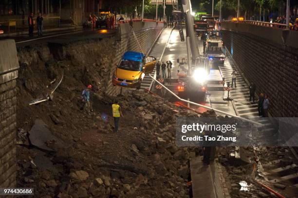 Rescue car pull the taxi out as the heavy rainstorm cause the wall collapse on a city street on June 14, 2018 in Harbin, China. Two people were...