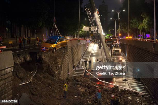 Taxi is shown having fallen to a lower roadway after a heavy rainstorm caused a wall collapse on a city street on June 14, 2018 in Harbin, China. Two...