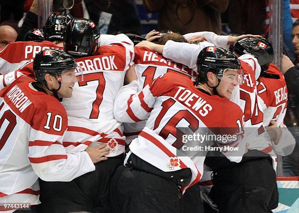 Brenden Morrow and Jonathan Toews of Canada celebrate with teammates around Sidney Crosby after Crosby scored the match-winning goal against USA in...