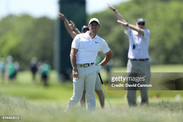 Rory McIlroy of Northern Ireland plays his second shot on the third hole as two marshals signal the ball has gone right during the first round of the...