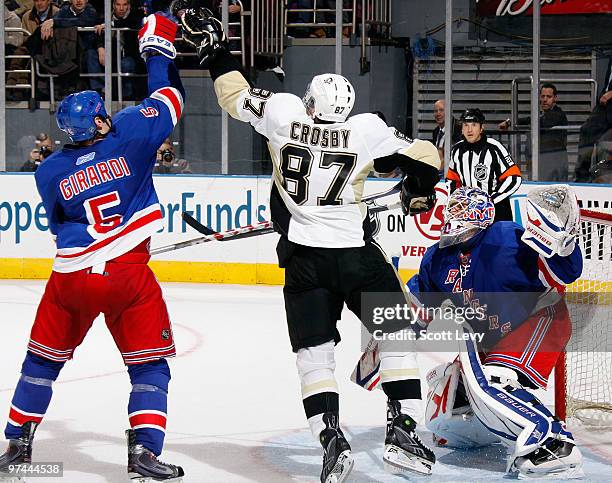 Dan Girardi of the New York Rangers reaches for the puck against Sidney Crosby of the Pittsburgh Penguins on March 4, 2010 at Madison Square Garden...