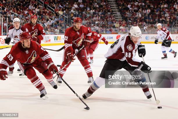Peter Mueller of the Colorado Avalanche skates with the puck past Derek Morris and Lee Stempniak of the Phoenix Coyotes during the third period of...