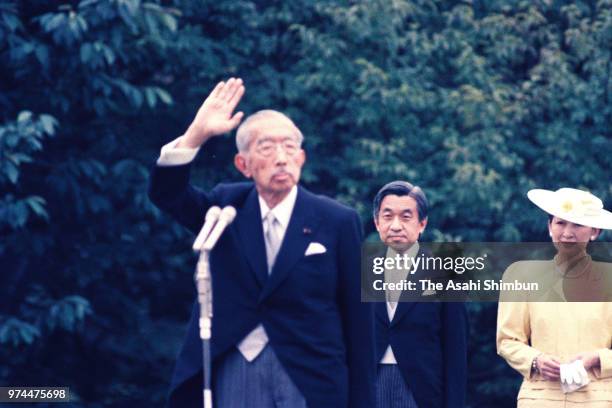 Crown Prince Akihito and Crown Princess Michio watch Emperor Hirohito waving to guests during the spring garden party at the Akasaka Imperial Garden...