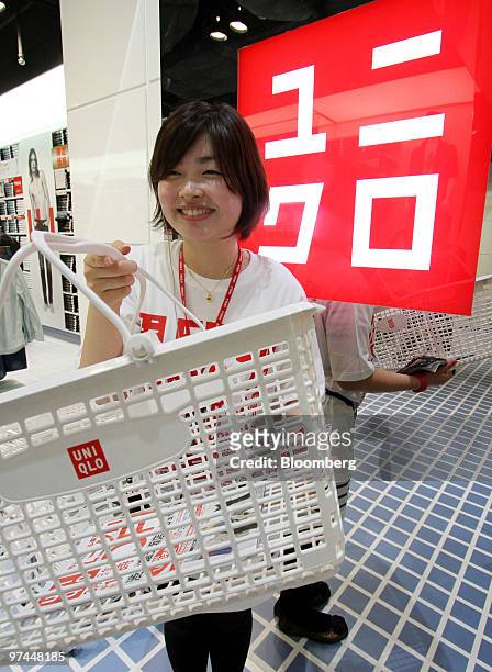 Shiori Yoshitake, an employee, hands a shopping basket to a customer at a Fast Retailing Co. Uniqlo store in Tokyo, Japan, on Friday, March 5, 2010....