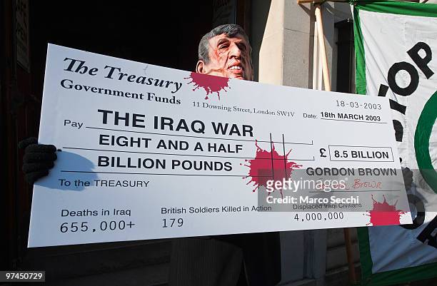 Protestor hold a giant cheque while Prime Minister Gordon Brown arrives at the Iraq Inquiry on March 5, 2010 in London, England. Mr Brown will face...