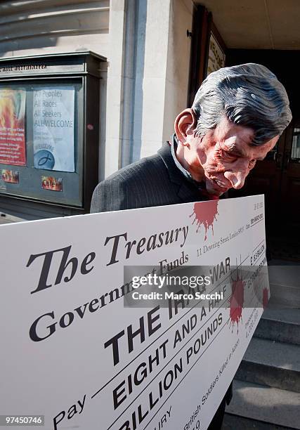 Protestor hold a giant cheque while Prime Minister Gordon Brown arrives at the Iraq Inquiry on March 5, 2010 in London, England. Mr Brown will face...