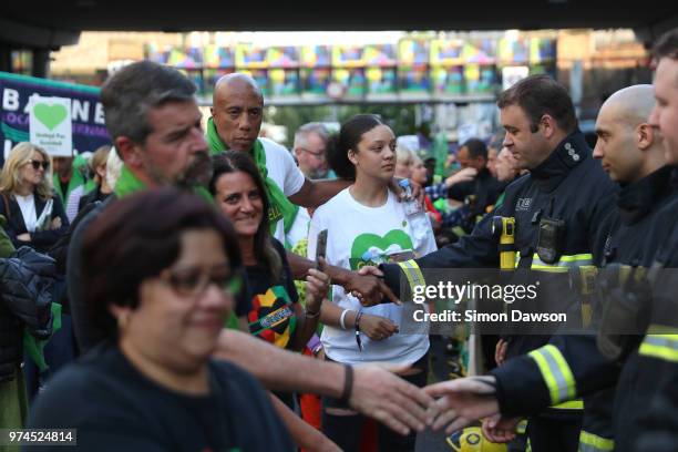 Participants shake the hands of firefighters during a silent march to St Marks Park where an open Iftar will take place on the one year anniversary...