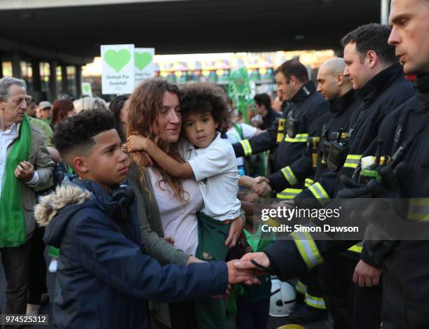 Participants shake hands with firefighters during a silent march to St Marks Park where an open Iftar will take place on the one year anniversary of...