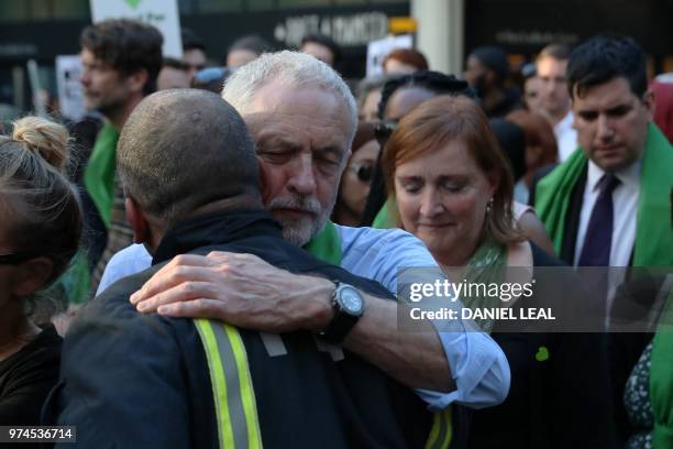 Britain's opposition Labour Party leader Jeremy Corbyn hugs a fire-fighter lining the street as members of the public take part in a silent march as...