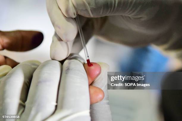 Health worker is seen drawing blood from a tribal woman. A health worker is collecting blood samples from tribal women and preserving them as the...