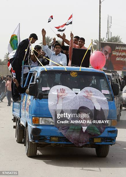 Iraqi men wave thir national flag as they ride at the back of a truck during an election campaign rally in Baghdad March 5, 2010. Politicians...