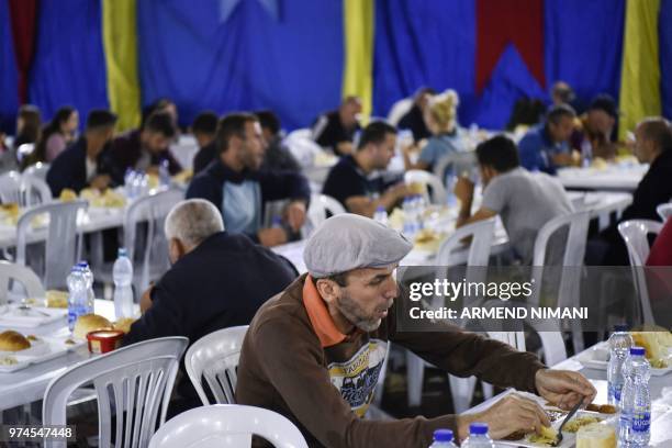 People receive a free Iftar meal as they break their fast during the last day of the Muslim holy month of Ramadan on June 14, 2018 in the Kosovo...