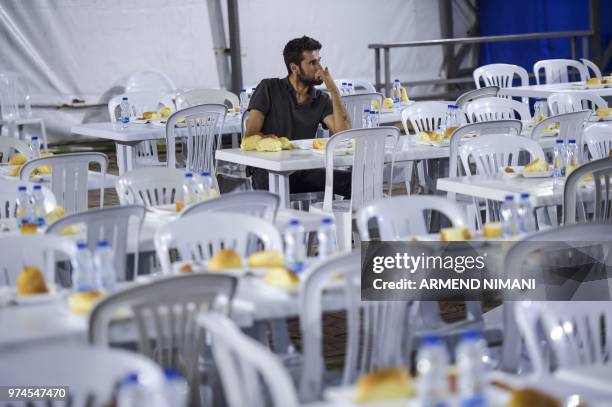 Man sits amid empty chairs as he receives free Iftar meal to break the fast during the last day of the Muslim holy month of Ramadan on June 14, 2018...