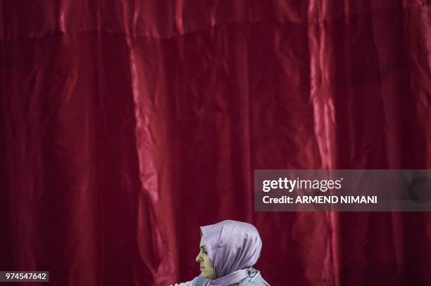 Woman sits as she receives a free Iftar meal to break the fast during the last day of the Muslim holy month of Ramadan on June 14, 2018 in the Kosovo...