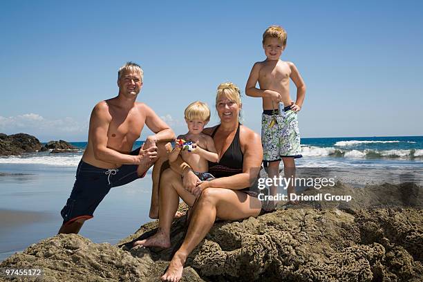 a family posing for a portrait on the beach. - front view portrait of four children sitting on rock stock pictures, royalty-free photos & images