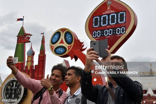 People take selfie pictures, with their mobile phone, in front of the digital FIFA World Cup 2018 countdown clock placed near the Red Square and the...