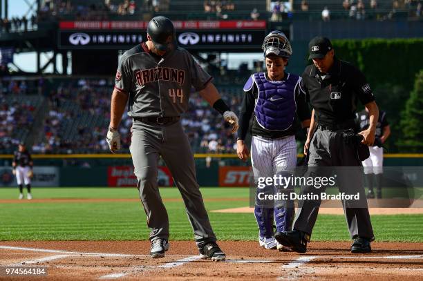 Paul Goldschmidt of the Arizona Diamondbacks touches home plate in front of Tony Wolters of the Colorado Rockies after hitting a first inning homerun...