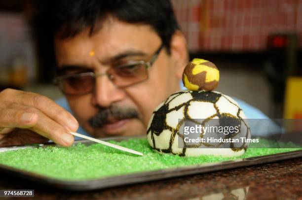 Nandalal's Sweet, a sweet maker prepares a football made with sweets to celebrate FIFA World Cup Football Tournament at the shop at Sukhia street, on...