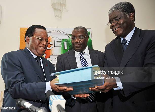 The new president of the Independent Electoral Commission, Youssouf Bakayoko receives a ceremonial dossier during the handover ceremony with his...