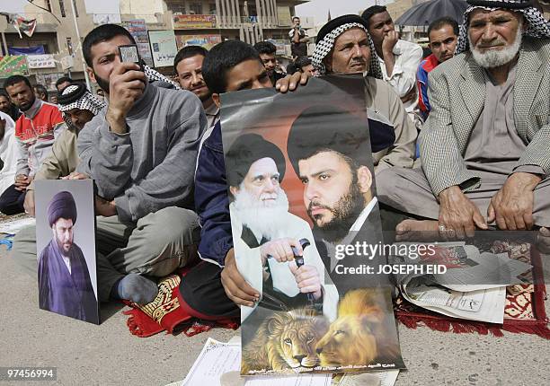 Iraqi Shiite Muslims hold posters of radical Shiite cleric Moqtada al-Sadr and his slain father Mohammed Sadeq al-Sadr as they attend Friday prayers...