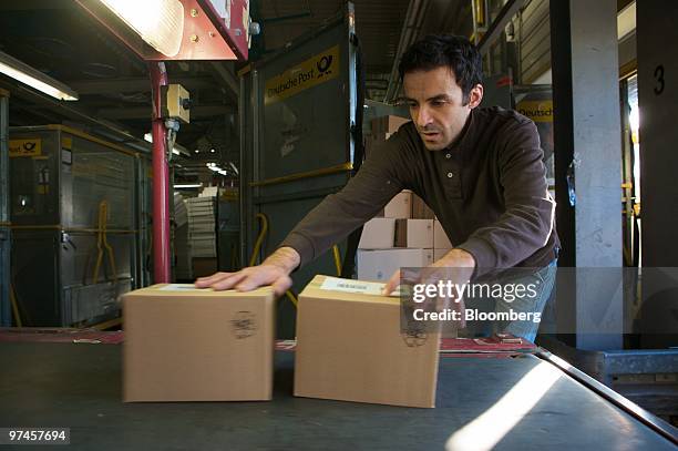 An employee loads parcels into a sorting machine at a package sorting center in Cologne, Germany, on Thursday, March 4, 2010. Deutsche Post AG...