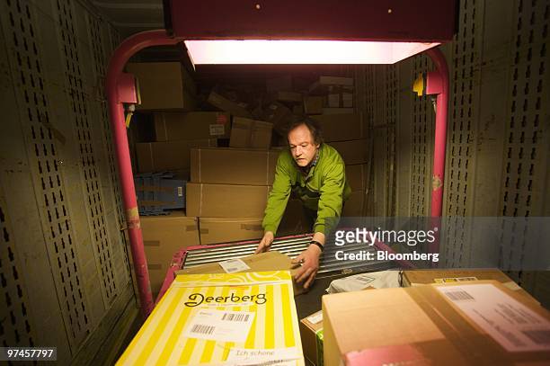 An employee puts sorted parcels from a conveyor belt for delivery at a DHL package sorting center in Cologne, Germany, on Thursday, March 4, 2010....