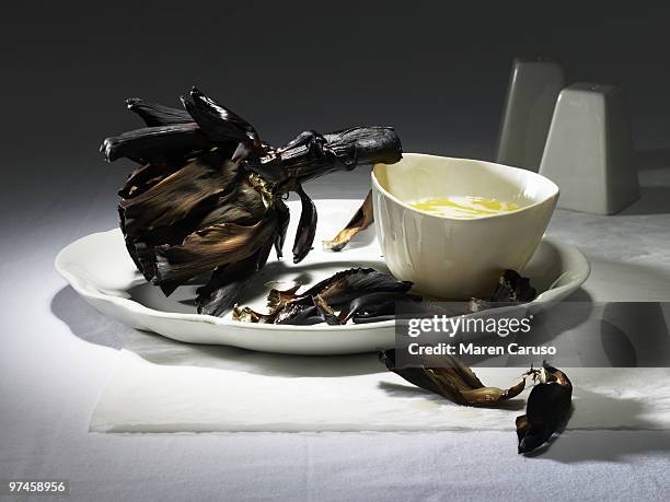 burnt artichoke with butter on a white plate - karzinogen stock-fotos und bilder