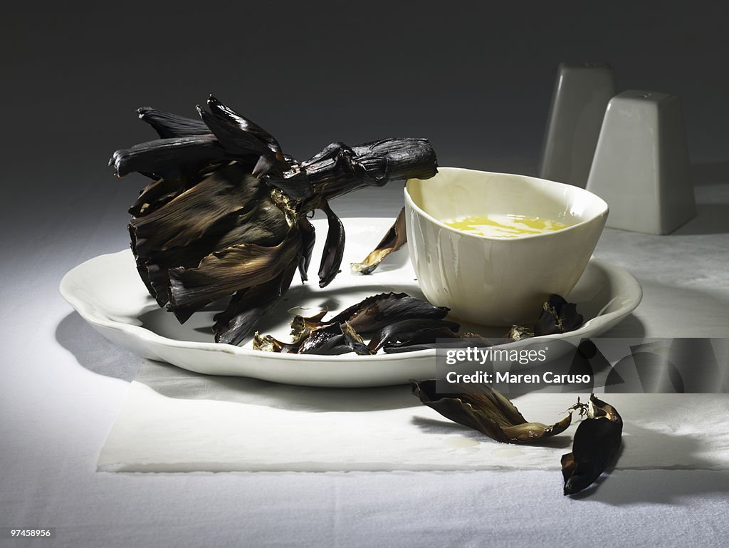 Burnt artichoke with butter on a white plate