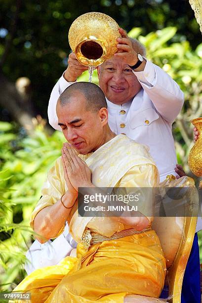 Cambodia's former King Norodom Sihanouk pours holy water on to his son, new King Norodom Sihamoni during a religious ceremony at the Royal Palace in...