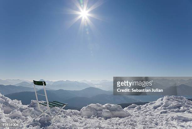 chair in show with sun against bavarian alps - lenggries stock-fotos und bilder