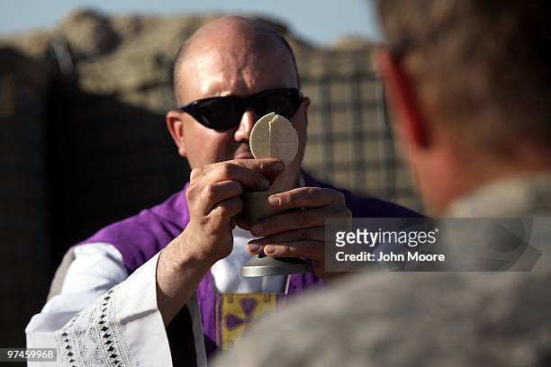 Army chaplain Carl Subler presents the Eucharist before distributing communion at a Catholic Mass for American soldiers on March 5, 2010 at a small...