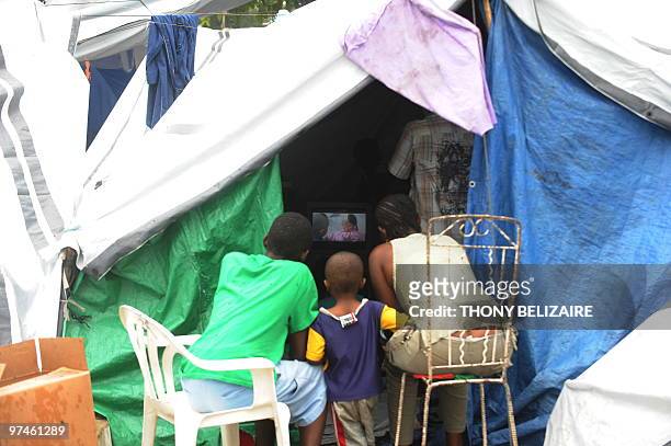 Haitian family watches television at a tent on March 5, 2010 in Port-au-Prince. A new round of food distributions will begin March 6 in quake-hit...