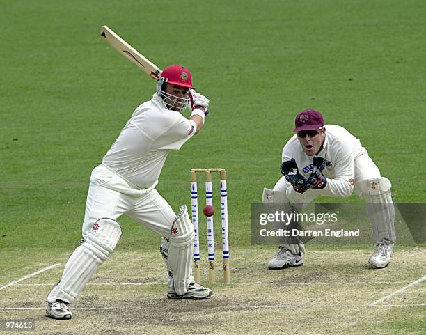 Darren Lehmann of South Australia hits four runs as Wade Seccombe of Queensland looks on during the Pura Cup cricket match played between Queensland...