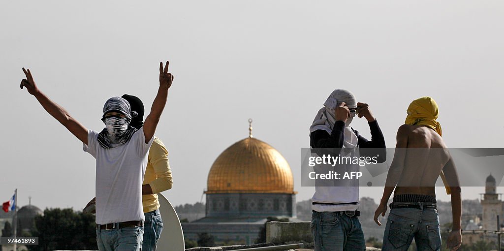 Masked Palestinian youths stand on a roo