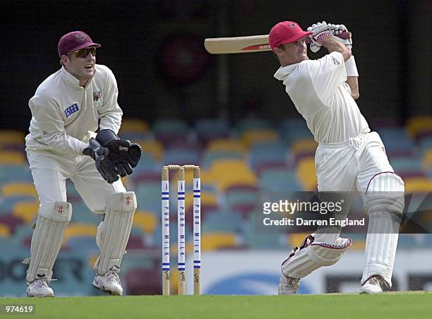 Greg Blewett of South Australia hits four runs as Wade Seccombe of Queensland looks on during the Pura Cup cricket match played between Queensland...