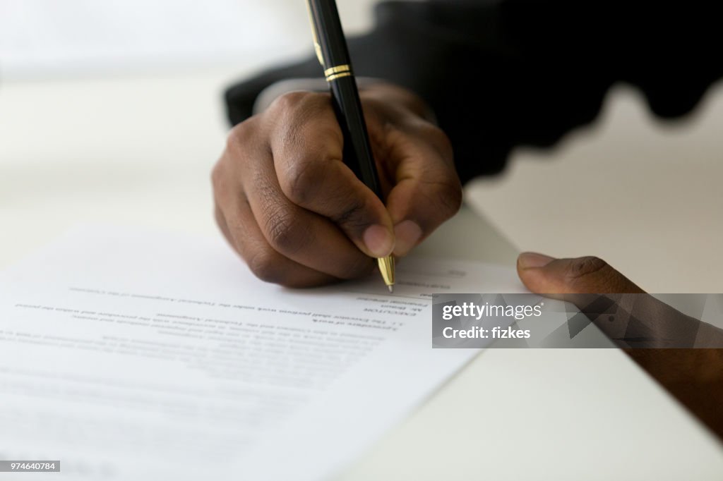 Close up of black worker signing legal documentation