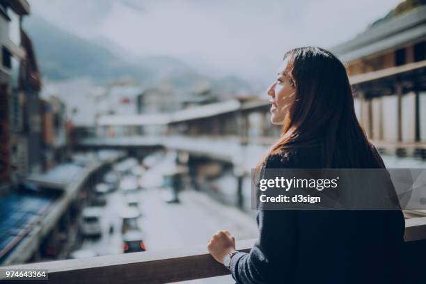 beautiful young woman standing on terrace looking at view with sunlight shining on - bridge side view stock pictures, royalty-free photos & images
