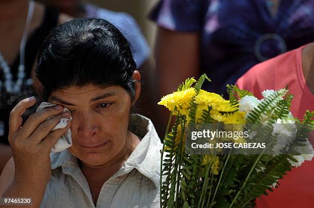 Woman wipes a tear during the burial of the 26 members of the Aleman and Rivera families slained during the civil war, at the cemetery in Suchitoto,...