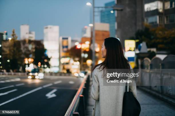 young woman waiting for a taxi ride in downtown city street at dusk - depois do trabalho imagens e fotografias de stock