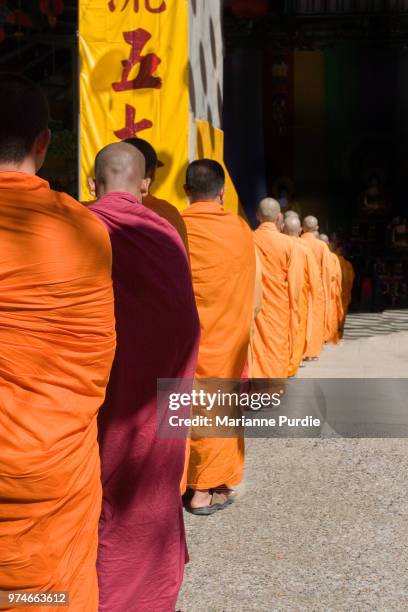 buddhist monks in saffron robes queueing for ceremonial role - theravada fotografías e imágenes de stock