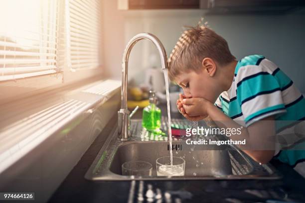 kleine junge trinkt leitungswasser - running water stock-fotos und bilder