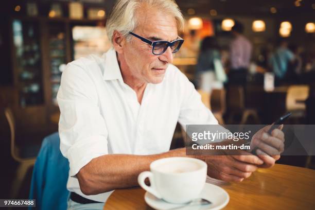 senior man in cafe using smartphone - senior romance stock pictures, royalty-free photos & images