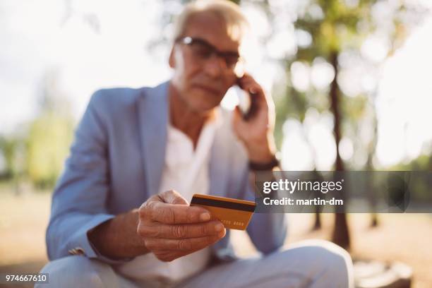 senior man having problems with credit card phoning the bank - debit card fraud stock pictures, royalty-free photos & images