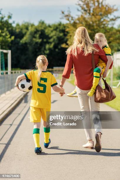 soccer mom accompanying her two daughters to football training - soccer mum stock pictures, royalty-free photos & images