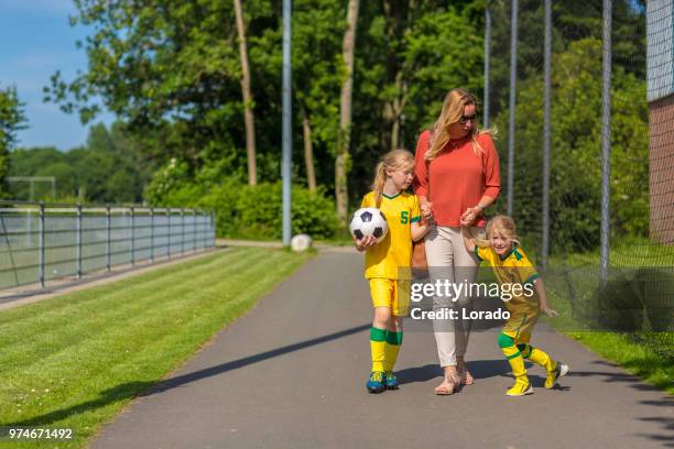 soccer mom accompanying her two daughters to football training - soccer mom stock pictures, royalty-free photos & images