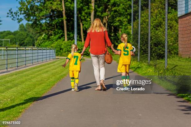 soccer mom accompanying her two daughters to football training - soccer mom stock pictures, royalty-free photos & images