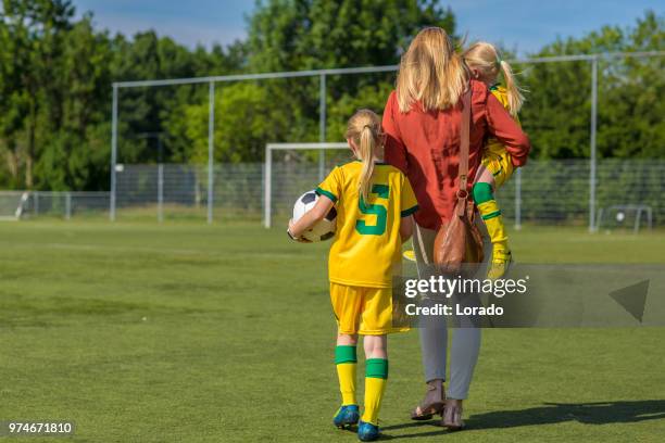 soccer mom accompanying her two daughters to football training - soccer mum stock pictures, royalty-free photos & images