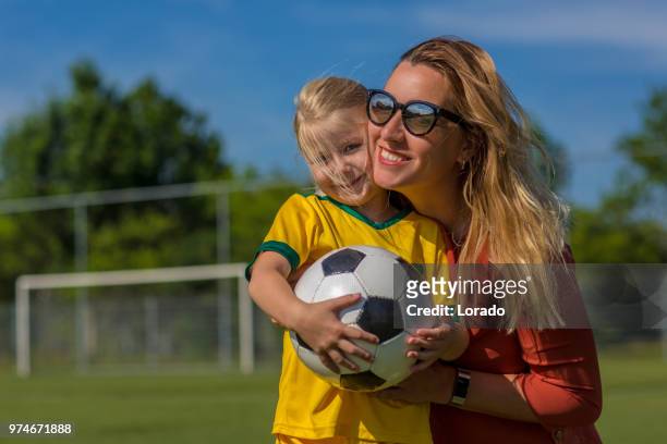 soccer mom preparing her blond daughter for football training - soccer mom stock pictures, royalty-free photos & images